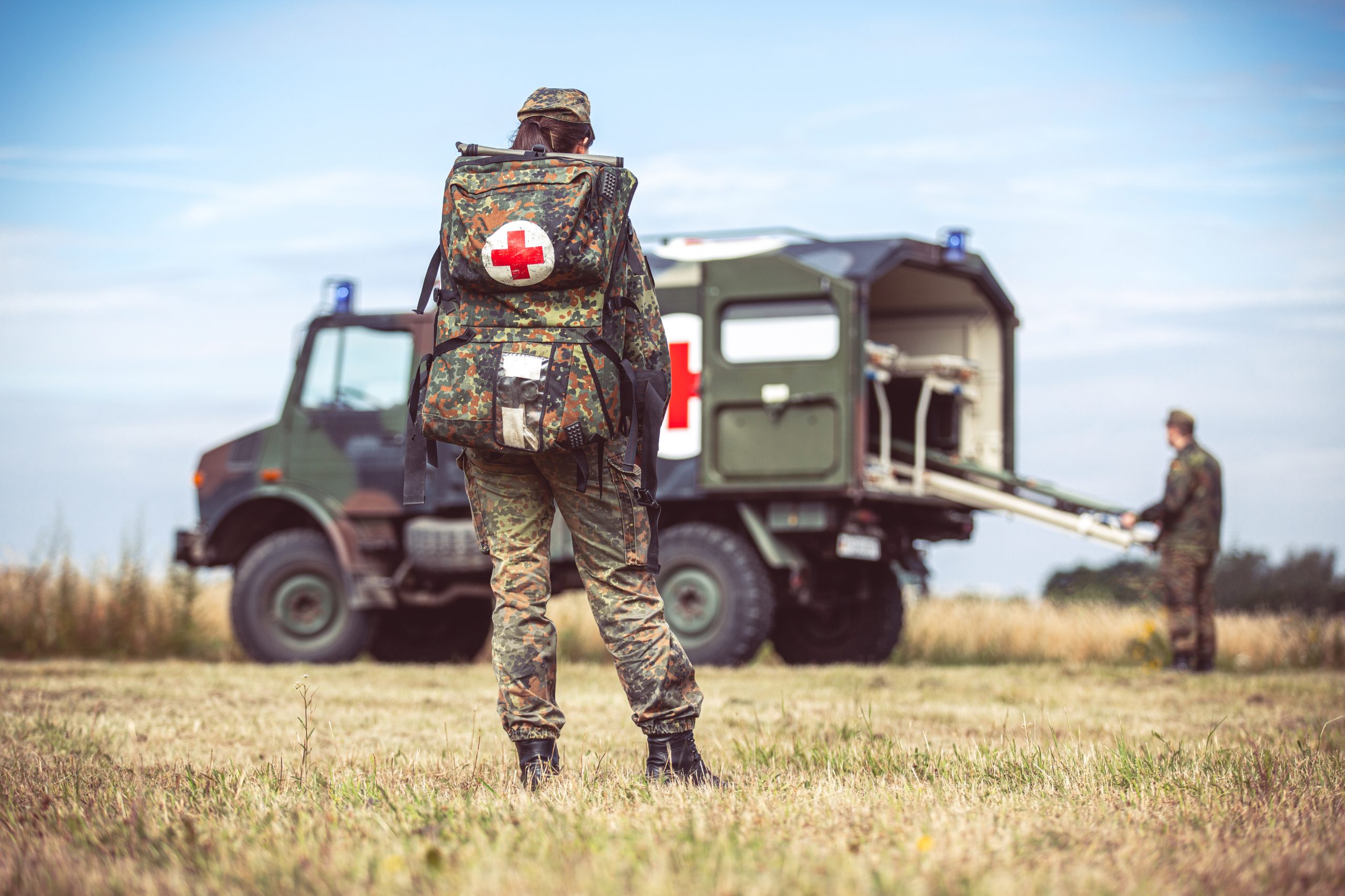 Hannover / Germany - June 24, 2020: Paramedic of the German army with an emergency backpack stands at a military ambulance