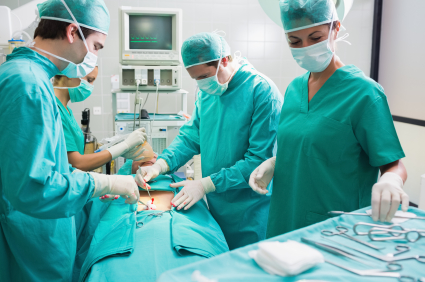 Nurse holding surgical tool next to operating table in an operating theatre